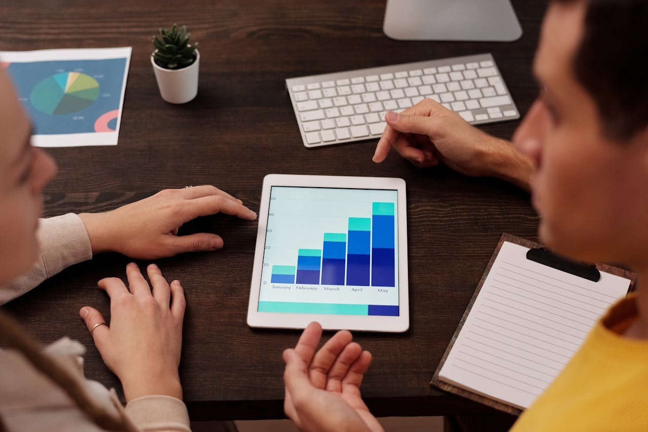 Team members discussing digital graphs on a tablet in a modern office setting.